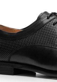 Schwarzer Lederschuh mit gewebter Textur auf dem Obermaterial, glatter schwarzer Spitze und niedrigem, gestapeltem Absatz. Verfügt über Schnürverschluss und tonale Naht.