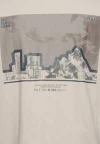Bawełniany t-shirt z szarym graficznym nadrukiem przedstawiającym panoramę miasta oraz góry, z napisem "OFF DUTY GEAR" oraz "HALO" w niebieskim i czarnym kolorze.