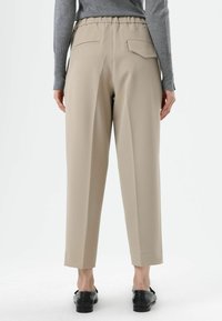 Beige, high-waisted trousers with a relaxed fit, featuring a flat waistband, side and back pockets, and a smooth fabric texture.