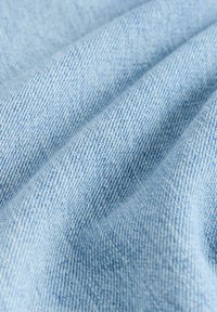 Țesătură de denim bleu deschis, cu o suprafață moale și texturată, având un model de țesătură fină și variații subtile în tonul culorii.