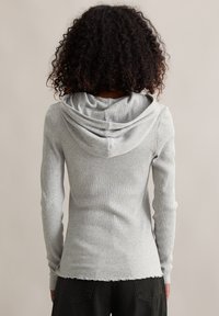 Lichtgrijs geribd longsleeve shirt met capuchon, met een gegolfde zoom en textuurstof.
