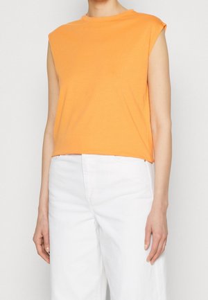 Orange ærmeløs top i blødt stof, med en afslappet pasform og rund halsudskæring, kombineret med højtaljede hvide bukser.