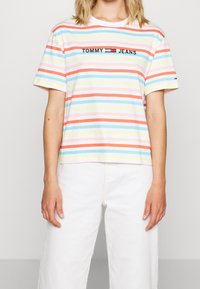 Gestreept t-shirt met korte mouwen in pastelkleuren, met geborduurd "TOMMY JEANS" logo. Gemaakt van zachte stof met een ontspannen pasvorm.