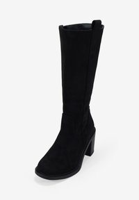 Botte noire montant en cuir suédé souple avec un talon large. Présente un haut incurvé, une texture lisse et des détails de coutures minimaux.