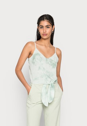 Camisola de alças finas em tie-dye verde claro com decote em V, combinada com calças altas verde claro e tecido amarrado na cintura.