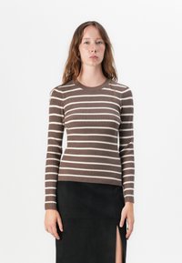 Brun og kremstribet ribbet sweater med lange ærmer, rund halsudskæring og tætsiddende design, parret med en sort nederdel med slidser på låret.