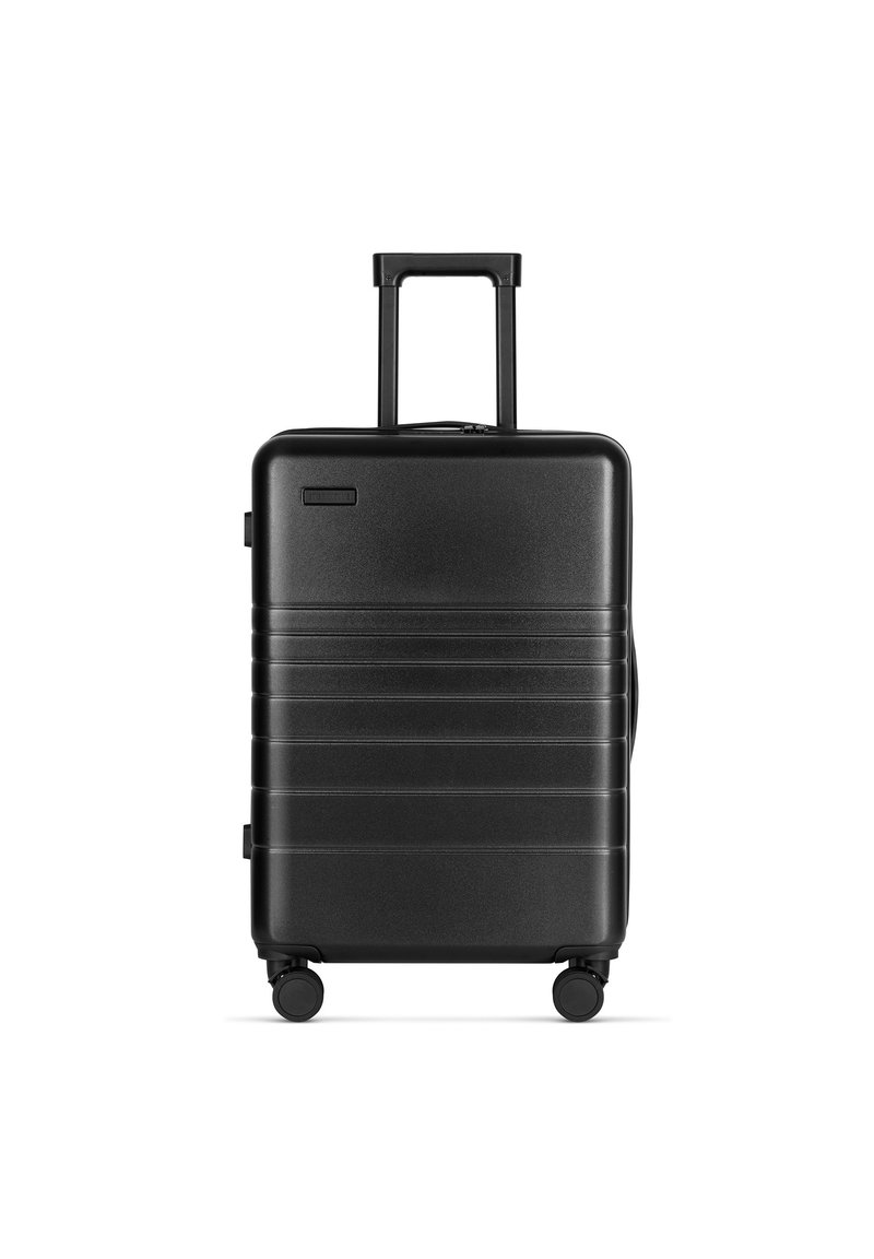Schwarzer Hartschalenkoffer mit glatter Oberfläche, horizontalen Rillen, ausziehbarem Griff und vier Rädern für einfache Mobilität.