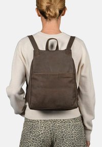 Bruine leren rugtas met een vierkante vorm, schouderbanden en een bovenhandgreep. Heeft een voorvak en een gladde textuur.