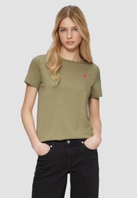 Oliwkowa bawełniana koszulka z krótkim rękawem i okrągłym dekoltem, z małym haftowanym czerwonym sercem na lewej piersi.