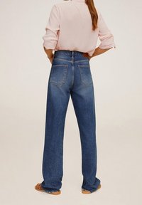 Hochgeschnittene, weit geschnittene Jeans aus mittlerem Blauton Denim mit strukturiertem Finish und hinteren Taschen. Kombiniert mit einem hellrosa Oberteil.