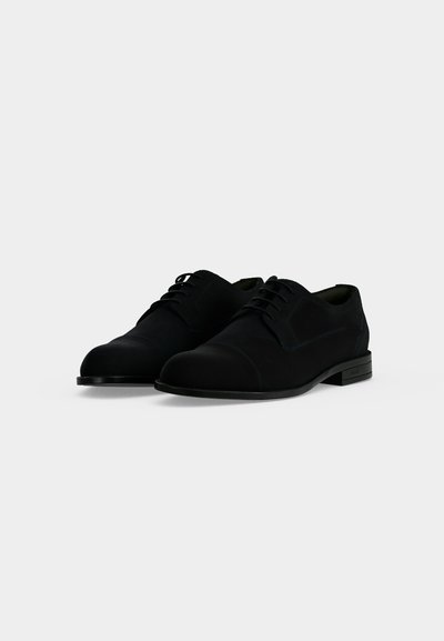 Paire de chaussures formelles noires à lacets pour hommes, talon bas, finition cuir lisse et bout arrondi sur fond blanc uni.