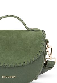 Sac à main en cuir vert avec une finition en daim, forme arrondie, accents tressés, quincaillerie dorée et une bandoulière amovible. Logo "HEY MARLY" visible.