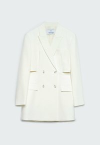 Blazer blanc croisé avec revers à encoches et manches longues, comprenant deux poches à rabat et quatre boutons sur le devant.