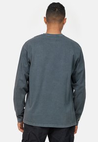 Langærmet t-shirt i kulgrå bomuld med rund hals, lige kant og afslappet pasform, der har synlige sømme og struktureret stof.