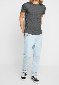 Gray short-sleeve t-shirt, light blue loose-fit jeans, and black Vans sneakers with white laces. Simple, casual outfit.