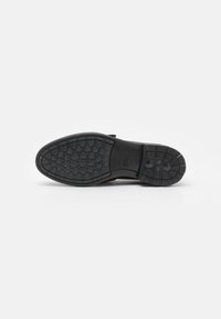Suela de zapato negra con agarre texturizado, que presenta un diseño de banda de rodadura y un borde suave. Material durable diseñado para proporcionar tracción y flexibilidad.