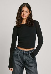 Svart långärmad cropped topp med rund halsringning, matchad med h�ögmidjade, mörkgrå jeans med sidofickor och en avslappnad passform.