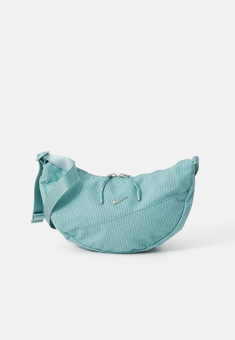 Teal textured pouch bag with a curved shape, featuring a zip closure, drawstring accents, and a small silver logo. Adjustable strap included.