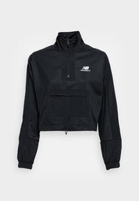 Cortavientos negro recortado con cuello alto, media cremallera, puños elásticos, bolsillo frontal y logo de New Balance en blanco en el pecho.