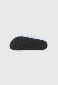 Blue shoe with a smooth upper, featuring a black rubber sole with a textured wave pattern for grip. Buckle detail near the ankle.