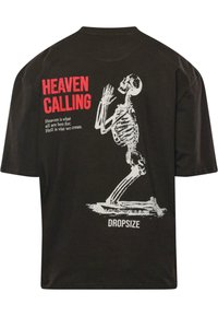 Sort bomulds T-shirt med et hvidt skeletgrafik, der knæler i bøn, med rød tekst "HEAVEN CALLING" og "DROPSIZE" på ryggen.