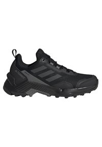 Chaussure de sport noire avec un dessus texturé, des panneaux en maille, trois bandes horizontales et une semelle extérieure robuste pour une meilleure adhérence.