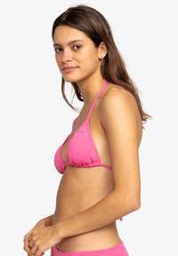 Růžový bikini top ve tvaru trojúhelníku s tenkými ramínky a nabíraným detailem ve spodní části, vyrobený z hladkého, elastického materiálu. Ozdoben malým logem.