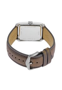 Bracelet de montre en cuir marron avec plusieurs trous, boîtier en acier inoxydable et finitions argentées. À l'arrière, on trouve un logo gravé et des détails sur la résistance à l'eau.