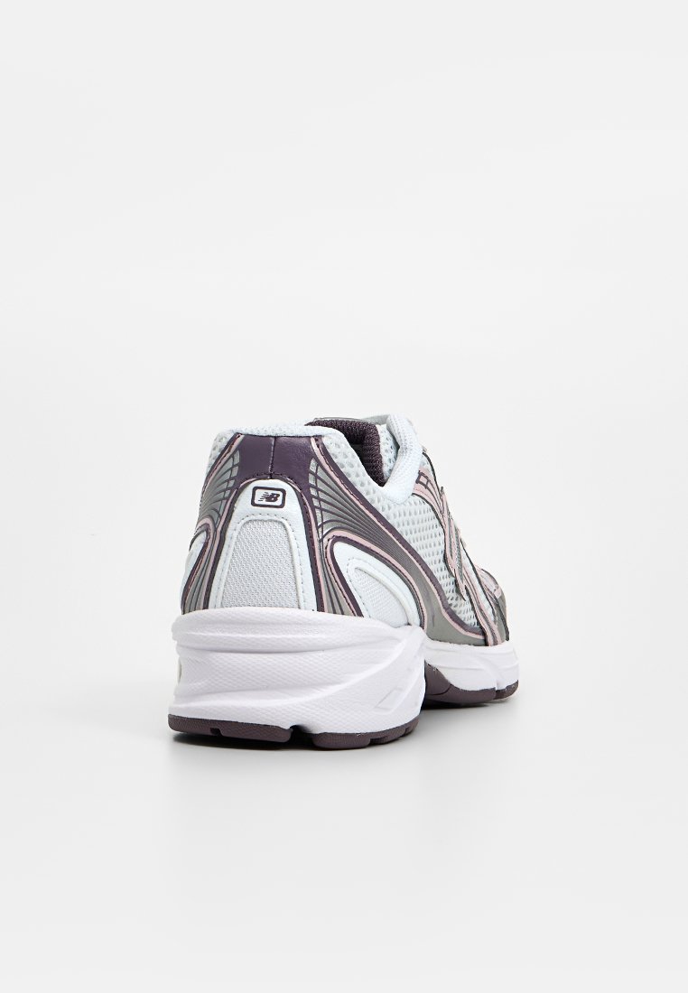 Graue und weiße Sportschuhe mit einem atmungsaktiven Mesh-Obermaterial, strukturierten Akzenten und einer gepolsterten Sohle, die ein reflektierendes Logodesign aufweisen.