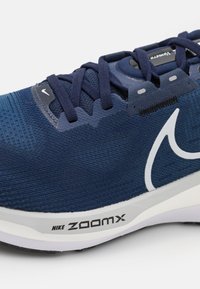 Scarpa da running Nike ZoomX in blu scuro, con una tomaia in mesh testurizzato, accenti neri prominenti e un logo bianco. Suola ammortizzata per un supporto ottimale.