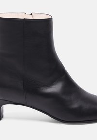 Botte de cheville en cuir noir avec une finition lisse, petit talon carré et bout arrondi. Dispose d'une doublure intérieure discrète et d'une fermeture éclair à l'arrière.