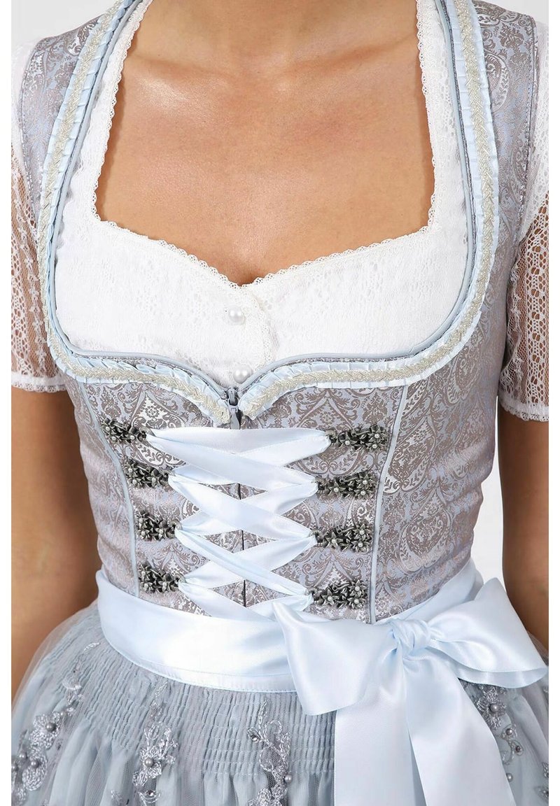Das Oberteil besteht aus silbernem gemustertem Stoff, weißen Spitzenärmeln, Perlenknöpfen und einem hellblauen Satinband, das in der Taille gebunden ist, kombiniert mit einem grauen Rock.