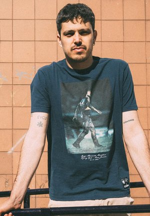 Navyblauwe T-shirt met korte mouwen, featuring een geprinte afbeelding van een figuur die loopt, met tekst eronder. Material lijkt zacht en heeft een casual pasvorm.