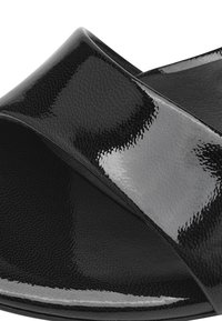 Zapato deslizante de charol negro con un diseño de tira cruzada ancha. Textura suave y brillante con punta redonda y talón abierto.
