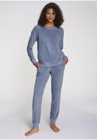 Soft blue loungewear set made of textured fabric. The top features a loose fit with ribbed cuffs, while the pants have an elastic waist and banded hems.