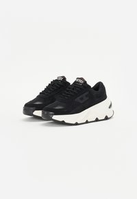 Black sneakers featuring a combination of suede and mesh, a chunky white sole, and black laces with a logo on the tongue.