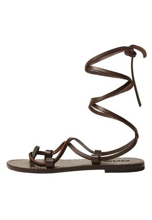 Sandale plate en cuir marron avec des fines lanières et un long lacet qui s'enroule autour de la cheville pour maintenir le pied.