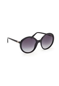 Lunettes de soleil rondes noires surdimensionnées avec des verres dégradés foncés et des branches fines sur un fond blanc.