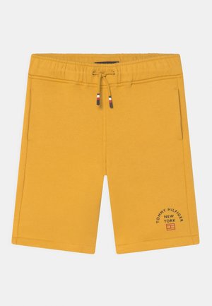 Żółte szorty z elastycznym pasem i sznurkiem, kieszeniami bocznymi oraz logo Tommy Hilfiger New York na dolnej lewej nodze.