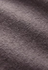 Zbliżenie na brązową tkaninę o teksturze z miękką, lekko puszystą powierzchnią oraz subtelnymi różnicami w odcieniach i splocie.