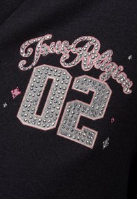 Tissu noir avec un design décontracté orné de strass argentés et roses. Inscription "True Religion 02" en lettres stylisées.