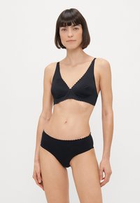 Conjunto de lencería negra que incluye un bralette con escote en v y borde ondulado, y unas braguitas de tiro alto a juego, ambos confeccionados en una tela suave.