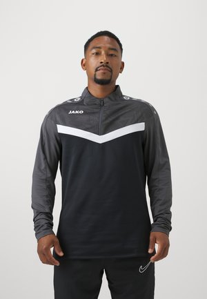 Schwarze und graue sportliche Zip-Jacke mit einem weißen Chevron-Muster, langen Ärmeln und Logo-Akzenten an den Schultern. Glatte Stoffstruktur.