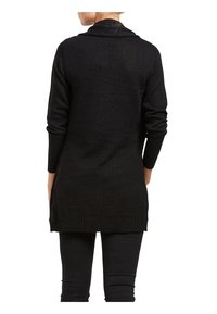 Zwarte trui met lange mouwen en een sjaalkraag, gebreide textuur en geribbelde zoom. Heeft een comfortabele pasvorm en valt net onder de heupen.