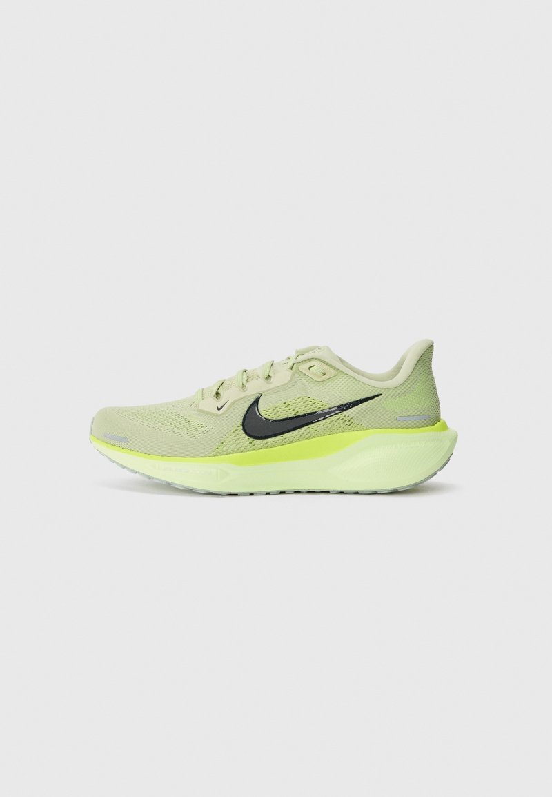 Chaussure de course Nike vert clair avec logo swoosh noir et semelle coussinée jaune fluo, vue de côté sur fond gris uni.