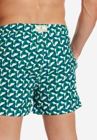 Costumi da bagno caratterizzati da un motivo verde e bianco con forme a onda e a punto. Vita elasticizzata con etichetta del marchio sul retro. Tessuto morbido.