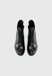 Bottines en cuir noir avec une finition lisse, bout rond, lacets à l'avant et zip sur le côté. Elles présentent un design minimaliste et une semelle robuste.