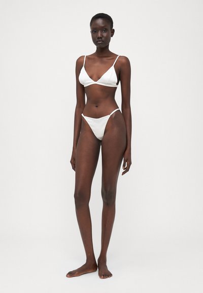 Set bikini bianco composto da un bralette triangolare e da un fondo tipo thong minimalista, realizzato in tessuto morbido con spalline sottili.