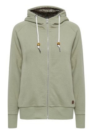Light green zip-up hoodie with a hood, white drawstrings, wooden bead accents, and a patterned interior lining. Soft, textured fabric.