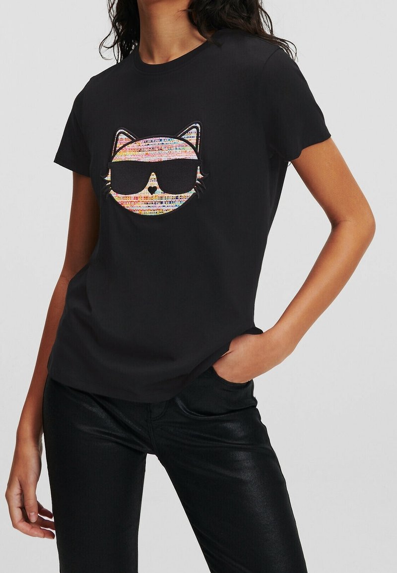 T-shirt nera con una grafica colorata di un volto di gatto con occhiali da sole. Maniche corte e tessuto morbido con una vestibilità rilassata.